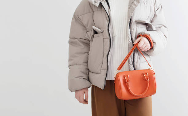 woman in  short down jacket with an orange handbag stock photo