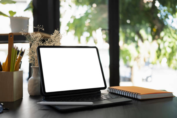 istock Mock up computer tablet, book and pencil holder on wooden table. 1354140238