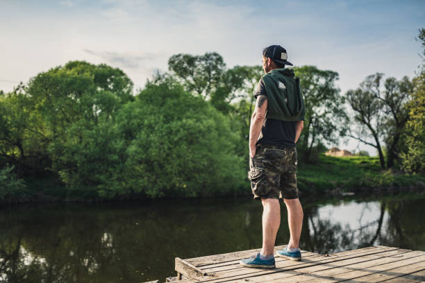 istock Man standing on the pier at river at sunset 1354140714