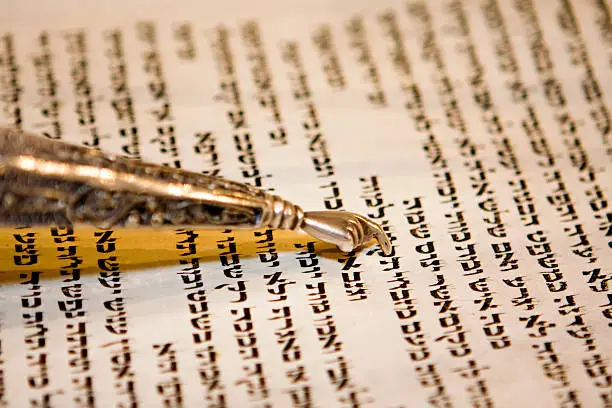 A traditional yad points to the Hebrew text of a torah during the reading of the parchment scroll during a bar mitzvah ceremony.