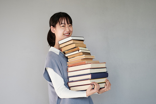 Portrait of Asian girl with stack of books