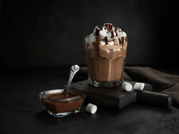 istock Cup of hot chocolate with marshmallow on a black background . 1354156431