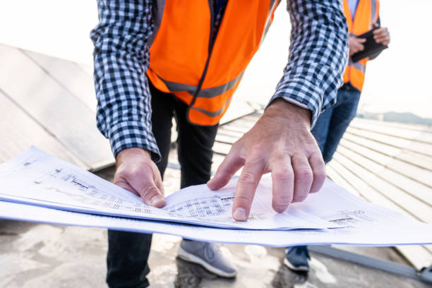 istock Male engineer holding plan while standing on the rooftop of solar power plant. 1354157448