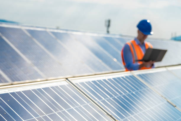 istock Male engineer using laptop while standing on the rooftop of solar power plant. 1354157471