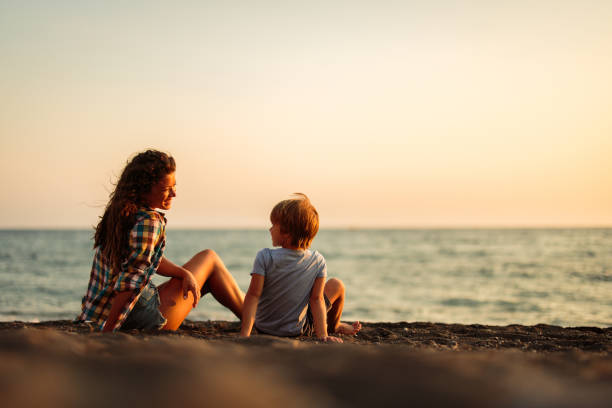 istock Happy single mother and son talking on the beach at sunset. 1354157597