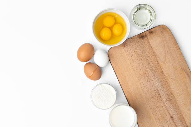 istock Baking background with raw eggs and wooden cutting board on white 1354158034