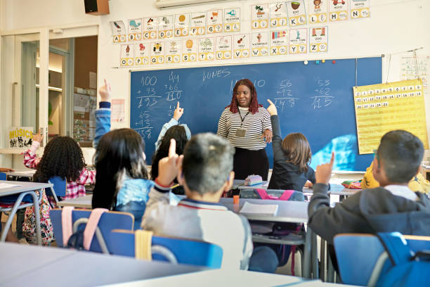 istock School Children Raising Their Hands in Arithmetic Class 1354158702