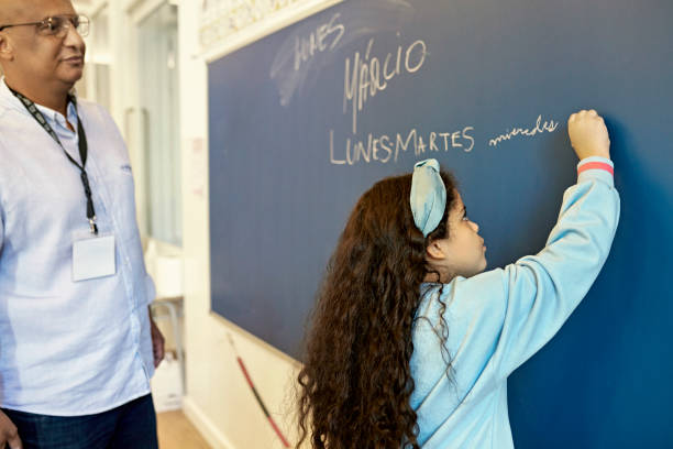 Teacher Watching 7 Year Old Girl Write on Board