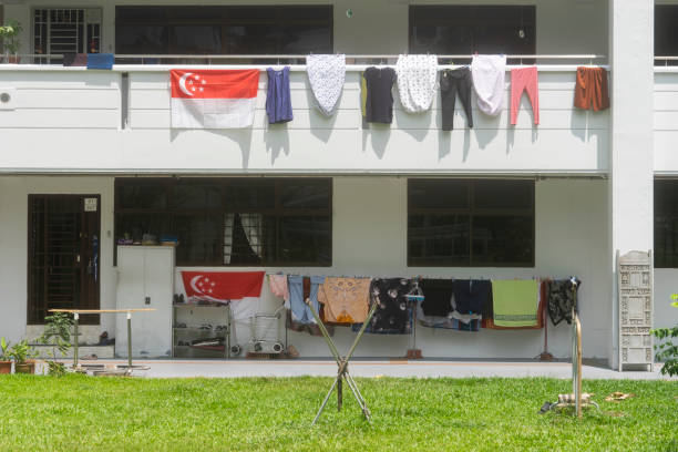 Multicolored clothes hang on drying racks outside apartment windows in Shanghai, China. The scene depicts urban living and daily life in the city.