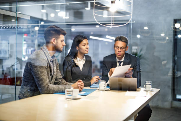 istock Couple going through paperwork with their agent in the office. 1354159815
