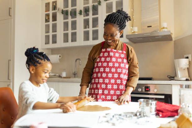 kleines mädchen, das mit einer großmutter weihnachtslebkuchenkekse macht - grandmother cooking baking family stock-fotos und bilder