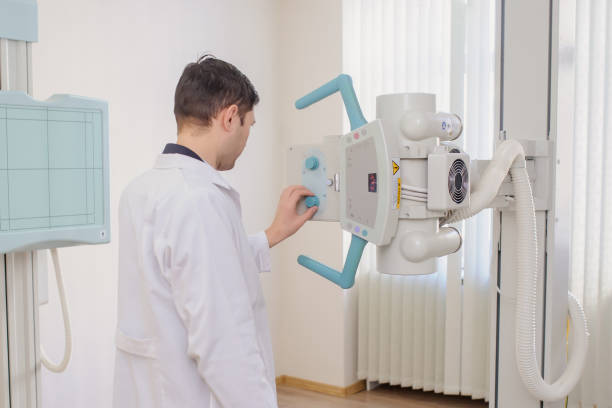 back view of a male radiologist adjusting the X-ray machine in examination rom