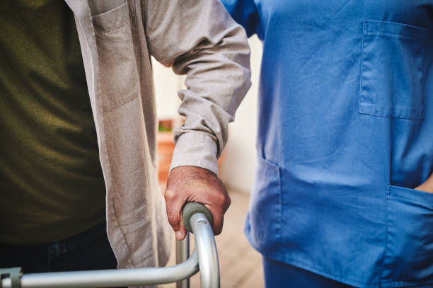 istock Cropped shot of an unrecognisable man using a walker outside while his nurse helps him 1354166323