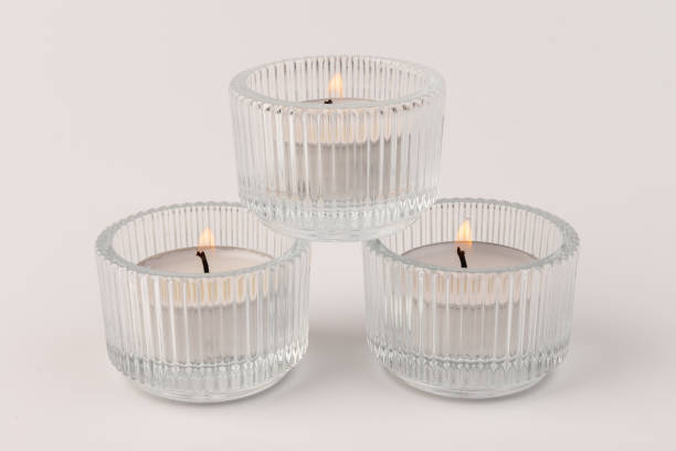 istock Burning tea candles in a glass holder, isolated on white. Space for text 1354166816