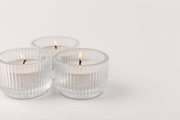 istock Burning tea candles in a glass holder, isolated on white. Space for text 1354166817
