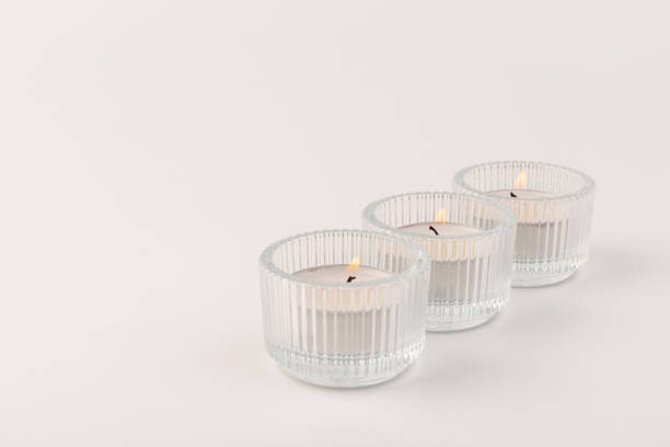 istock Burning tea candles in a glass holder, isolated on white. Space for text 1354166821