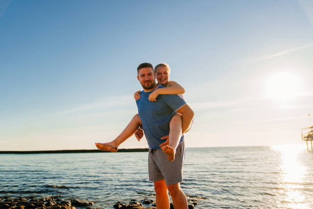istock Dad rides his daughter on back on the seashore. 1354167874