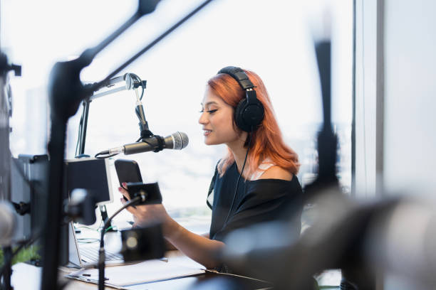 Focus on female podcaster live streaming show The focus of the photo is on the mid adult female podcaster live streaming a show.  She is in a modern studio with state-of-the-art equipment. radio dj stock pictures, royalty-free photos & images