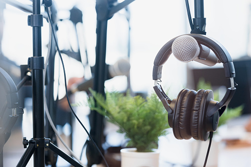 A close up photo of headphones hung on a microphone in a bright, cheerful recording studio.