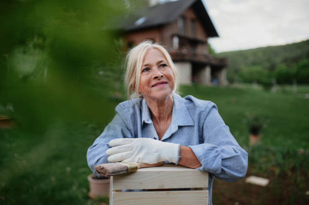 istock Happy senior woman sitting and resting while doing paint craft outdoors in garden. 1354171005