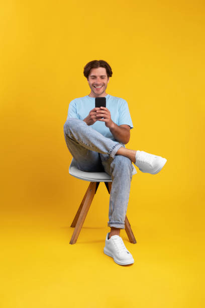 istock Happy guy using cellphone at studio, sitting on chair 1354171131