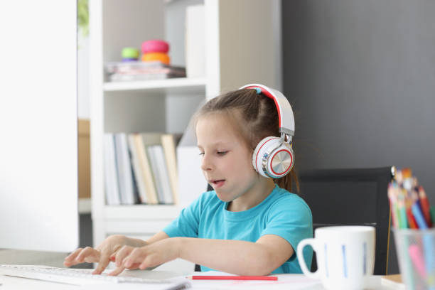 istock Cute kid wearing headset and typing on keyboard with effort 1354171339