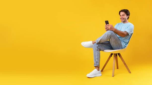 istock Happy guy using cellphone at studio, sitting on chair, banner 1354171789