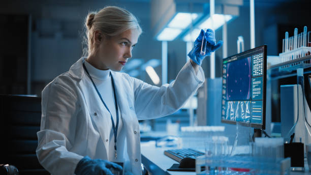 医学研究所:コンピュータに取り組む女性科学者の肖像画、ラブラトリーフラスコの液体サンプルを分析する。医学・バイオテクノロジー・ワクチン開発研究科 - scientist research group of people analyzing ストックフォトと画像