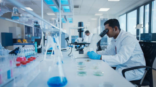 istock Modern Medical Research Laboratory: Male Scientist Working with Microscope, Analysing Biochemicals Samples. Advanced Scientific Lab for Medicine, Microbiology Development. 1354172461