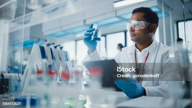 Medical Research Laboratory Portrait Of A Handsome Male Scientist Using Digital Tablet Computer Analysing Liquid Biochemicals In A Laboratory Flask Advanced Scientific Biotechnology Laboratory Stock Photo - Download Image Now