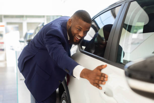 購入後にショールームで新しい車に触れるスーツでハッピーブラックビジネスマン - car african descent shopping car dealership ストックフォトと画像