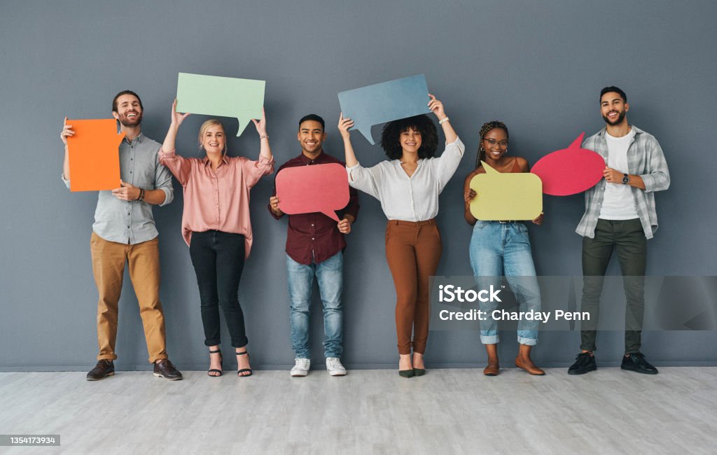 Full length portrait of a young and diverse group of businesspeople holding up blank placards in the shape of speech bubbles against a grey background in studio Let your voice be heard Speech Bubble Stock Photo