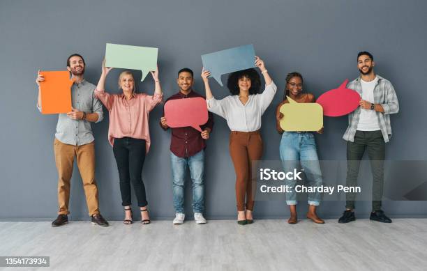 Full Length Portrait Of A Young And Diverse Group Of Businesspeople Holding Up Blank Placards In The Shape Of Speech Bubbles Against A Grey Background In Studio Stock Photo - Download Image Now