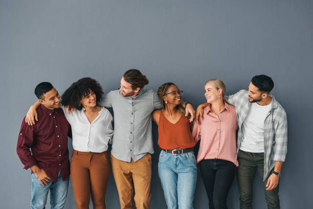 Cropped shot of a young and diverse group of businesspeople standing together against a grey background in studio They're more than just colleagues arm around stock pictures, royalty-free photos & images