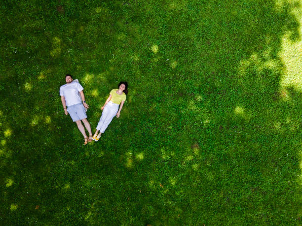istock smiling couple laying down on green grass 1354174762