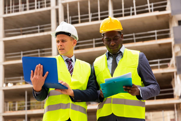 istock Architect and foreman must write documents and drawings on laptop with building construction 1354174904