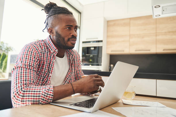 istock Upset guy sitting at his laptop in kitchen 1354175644