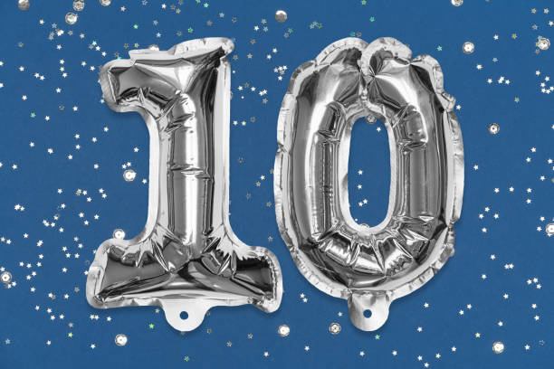 istock Silver foil balloon number, digit ten on a blue background with sequins. Birthday greeting card with inscription 10. 1354175697