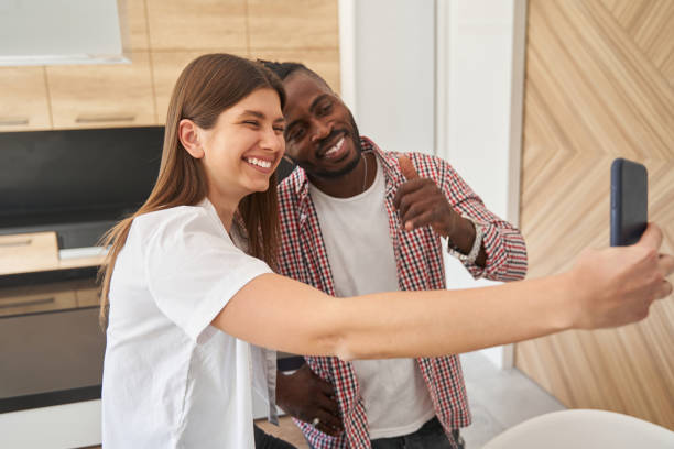 istock Joyous mixed-race couple posing for smartphone camera 1354175737