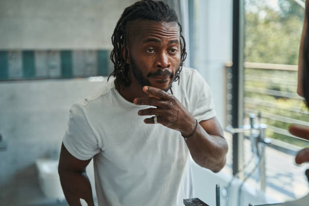 istock Focused guy examining skin on his face 1354175930