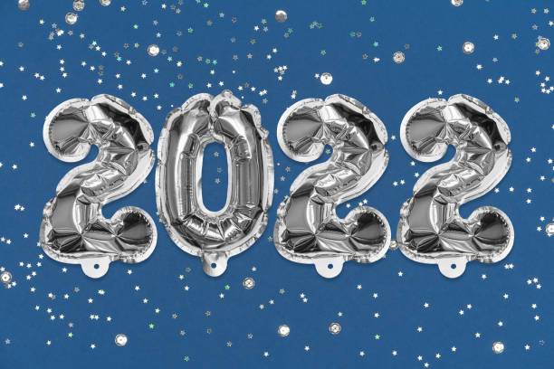 istock Silver foil balloon number, digit 2022 on a blue background with sequins. New Year's card. 1354176392