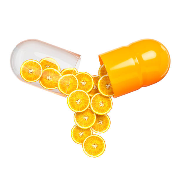 Amber glass tumbler filled with water and a straw, surrounded by golden capsules on a light surface under warm sunlight, creating a glowing effect.