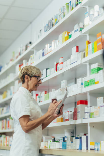 istock Beautiful senior female pharmacist checking medications on a shelf 1354176618