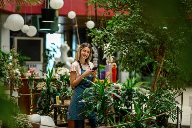 istock Florist taking care of a plant while using a smartphone 1354176633