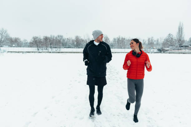istock Young couple going for a run together during a snow on a cold winter day 1354176666