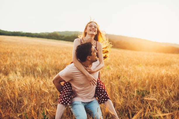 pareja joven divirtiéndose en el campo de trigo. paseos en alcancía. fin de semana familiar. - human relationship fotografías e imágenes de stock