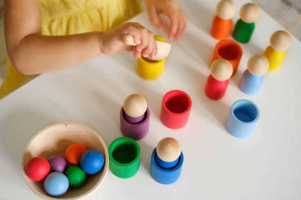 子供はスプーンで適切な色のカップにボールを投げます。 - fine motor skills ストックフォトと画像