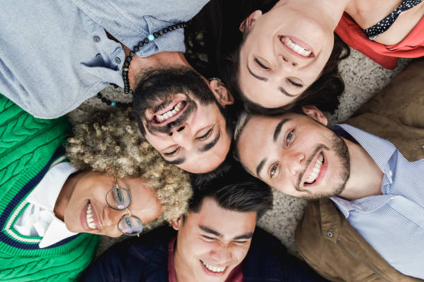 istock Young multiethnic people lying in circle while having fun outdoor - Focus on right man face 1354178263
