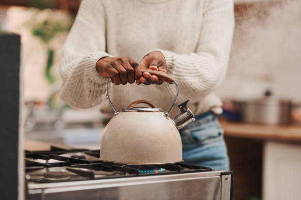 Shot of an unrecognizable person boiling water on the stove at home stock photo