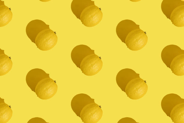 Pattern of whole lemon on yellow background with a hard shadow. The concept of summer, fruits, vitamins. stock photo